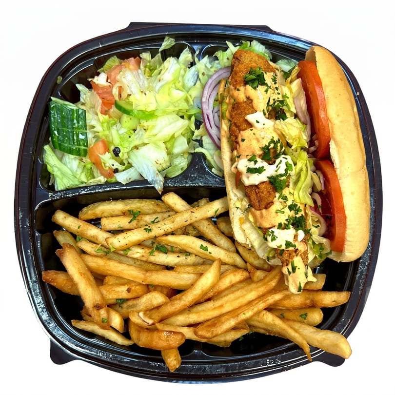 Fried fish po'boy with lettuce, tomato, and sauce, served with fries and a side salad.