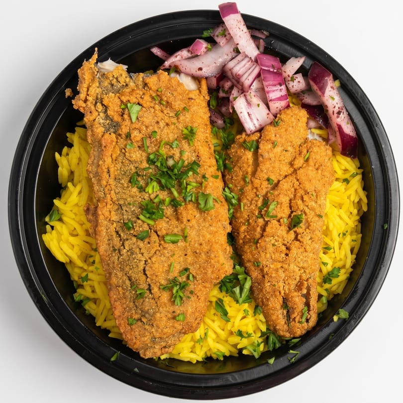 Fried fish fillets with yellow rice and pickled red onions in a black takeout container.