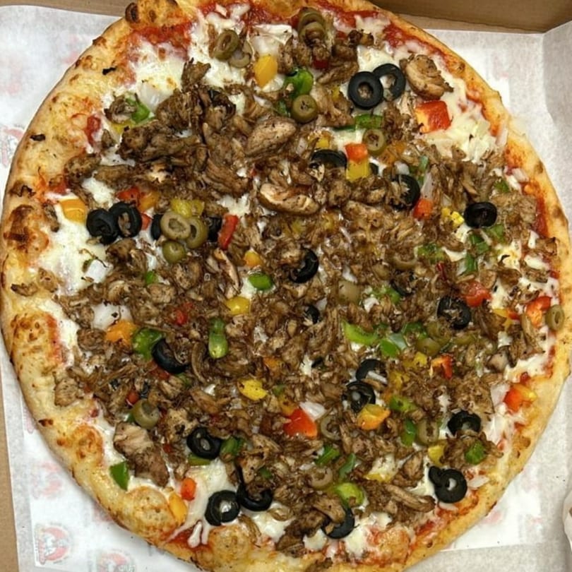 A whole pizza topped with shredded chicken, black and green olives, and colorful bell peppers.